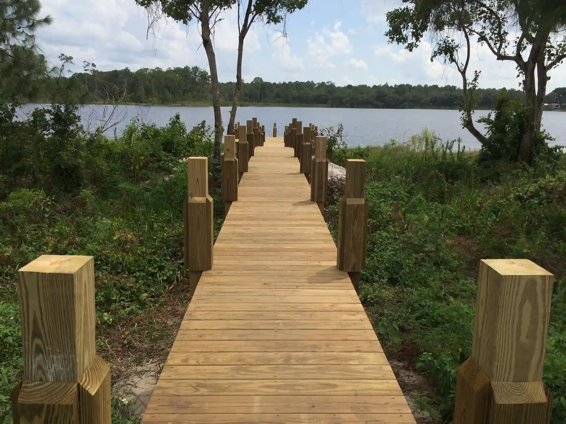 wooden path to a boat dock along the water - Composite Dock Builders near me Central Florida