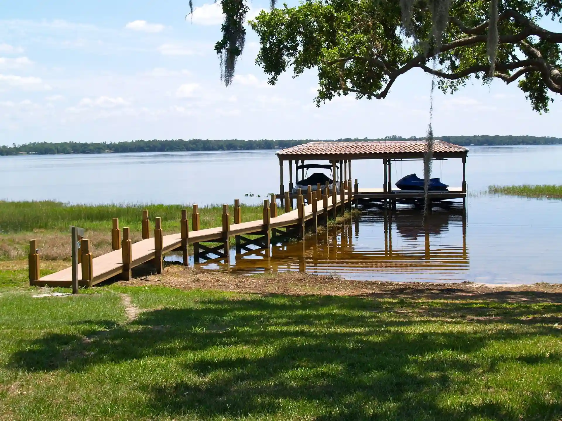 photo of a walkway leading out over the water to a covered boat dock - Deck Remodeling and Dock Restoration Services near me in Central Florida