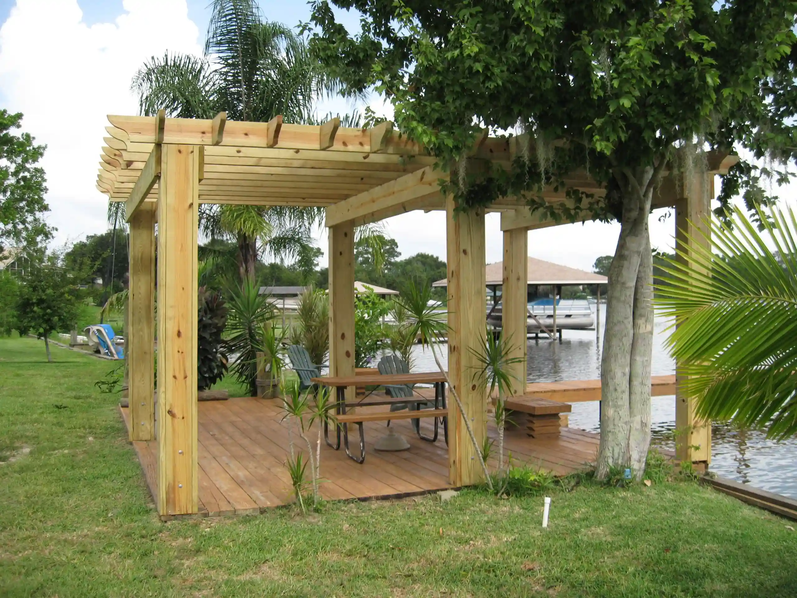 photo of a traditional wooden pergola on a waterfront wooden deck