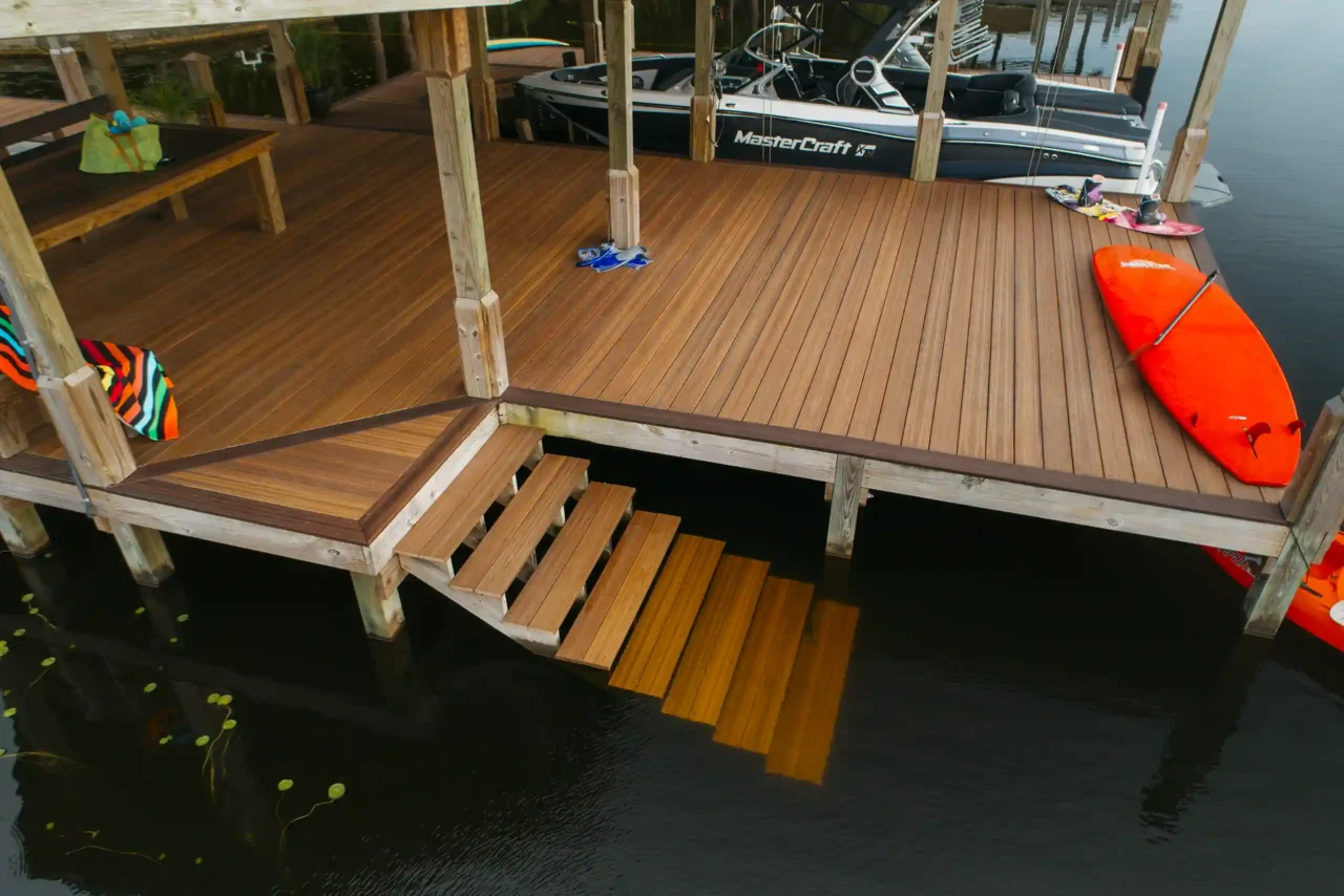 Photo of a waterfront deck with composite wood, floating stairs, and boat dock. A red kayak and MasterCraft boat are nearby.